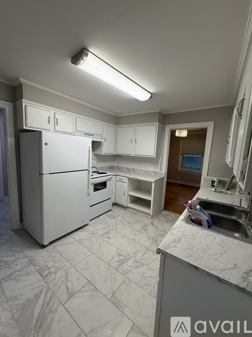 A black refrigerator stands in a kitchen with green cabinets.