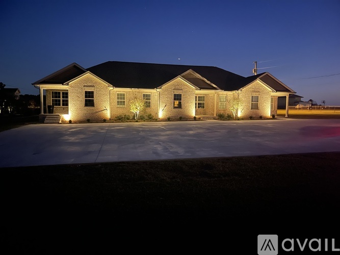 A house with lights on and a sign that says "AVAIL" in front of it.
