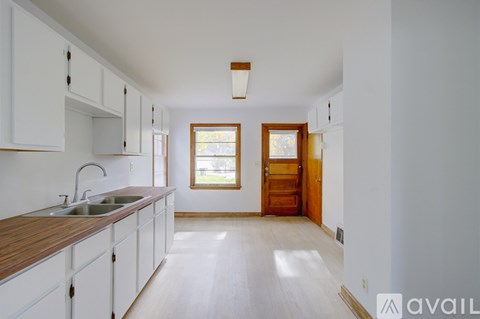 A kitchen with white cabinets and a wooden counter top.