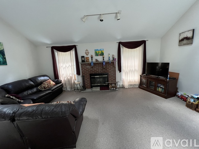 A living room with a black leather couch and a fireplace.