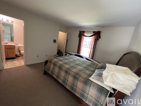 A bedroom with a bed, a mirror, and a window with red curtains.