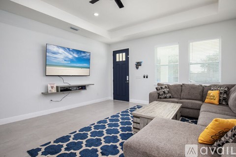 A living room with a grey couch and a blue and white rug.
