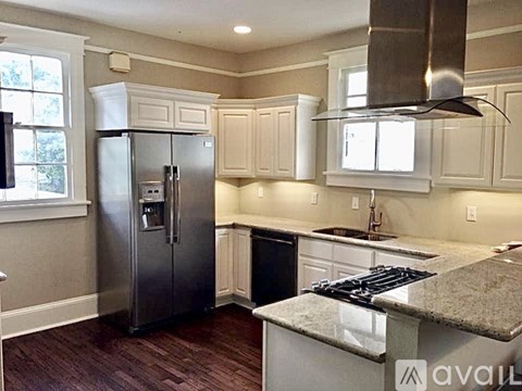 A kitchen with a stainless steel refrigerator and a granite countertop.