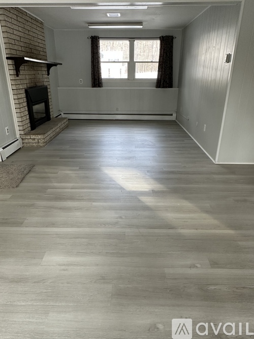 A spacious living room with a fireplace and wood flooring.