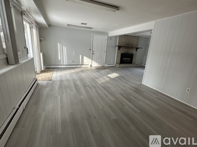 A spacious room with wooden flooring and white walls.