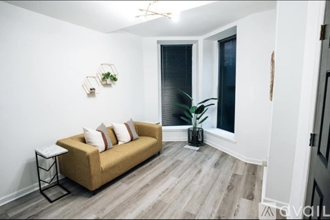 A living room with a yellow couch and a plant on the side table.