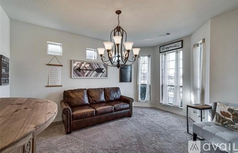 A living room with a brown leather couch and a wooden table.