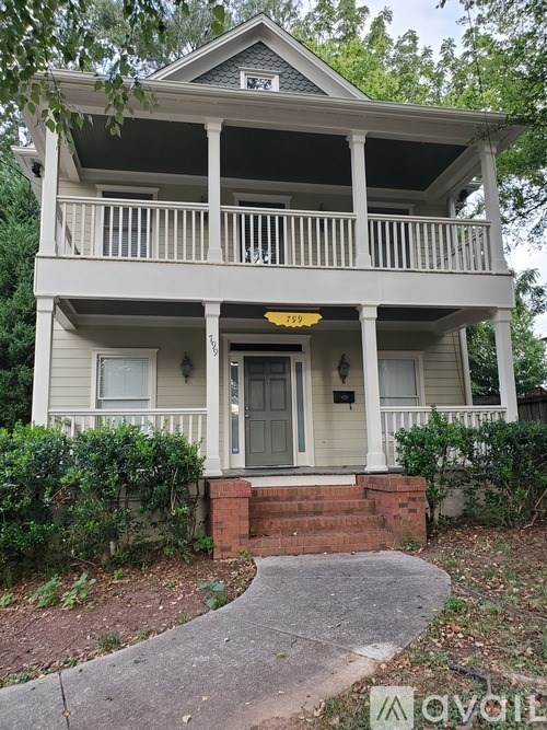A two-story house with a front porch and a mailbox on the front door.