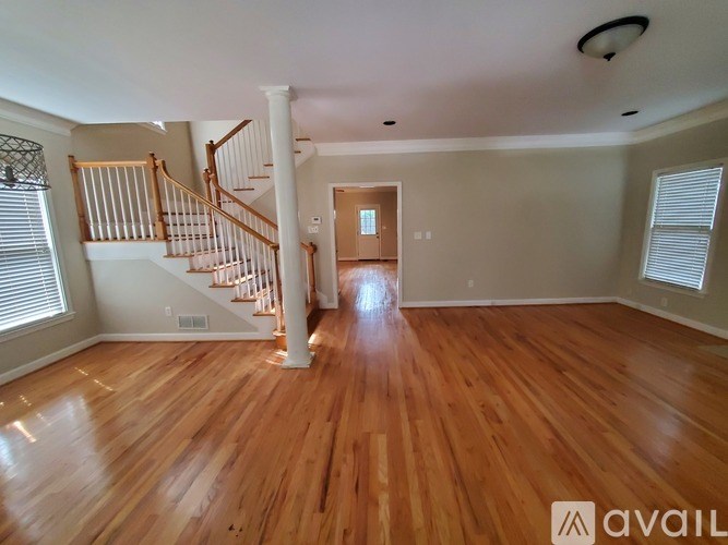 A spacious room with wooden floors and a staircase leading to another level.