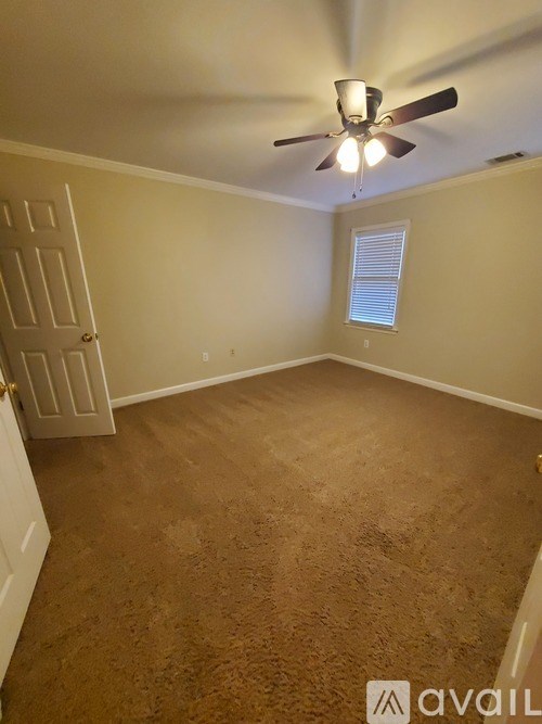 A room with a ceiling fan and carpeted floor.