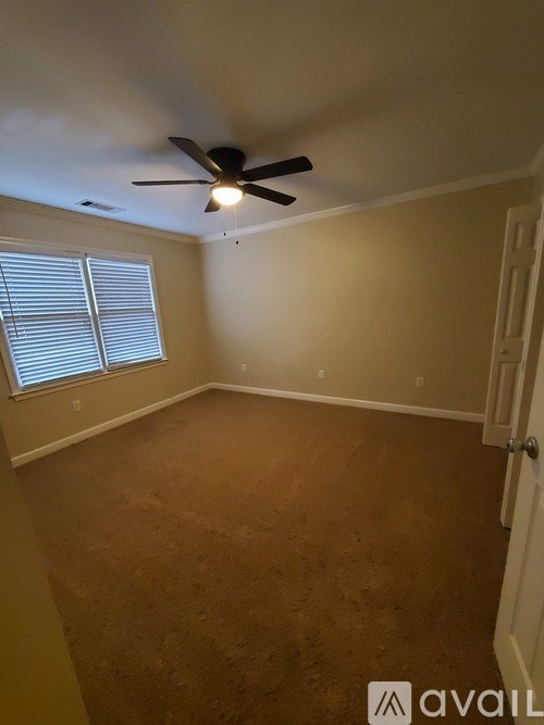 A room with a ceiling fan and a window with blinds.