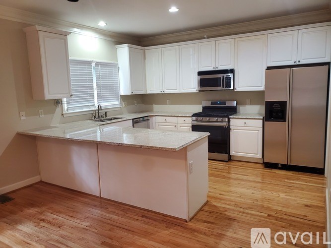A kitchen with white cabinets and a wooden floor.