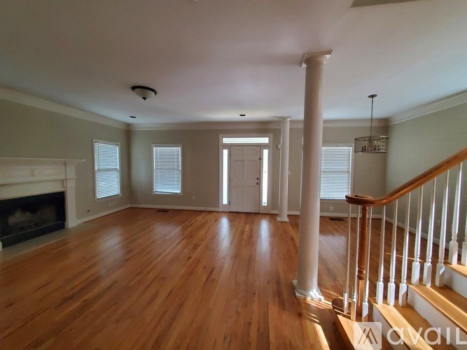 A large empty room with wooden floors and a staircase.