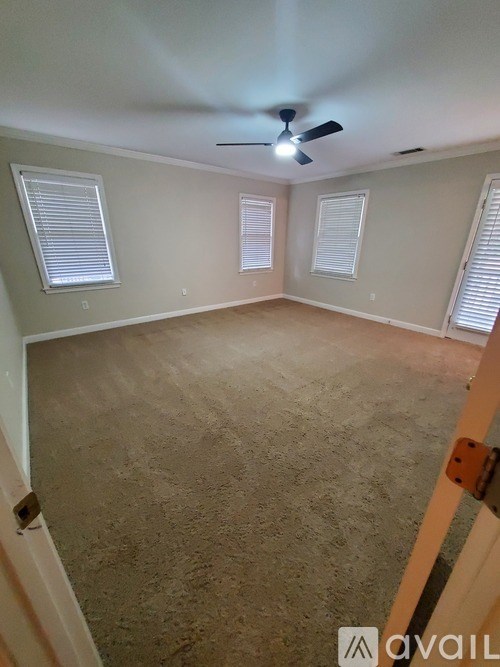 A room with a ceiling fan and carpeted floor.