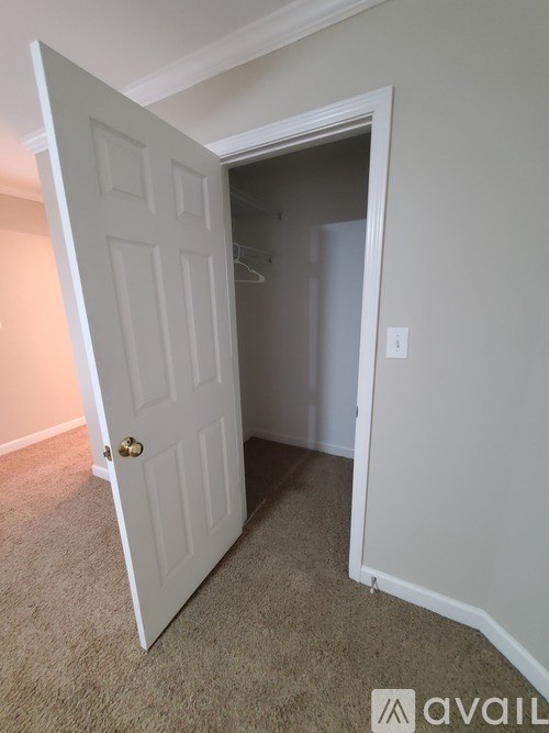 A white door is open to a room with a carpeted floor.