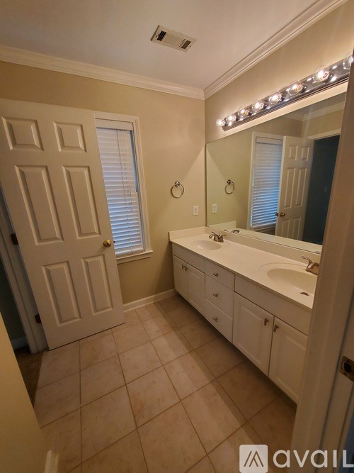 A bathroom with a white vanity and a mirror with lights above it.