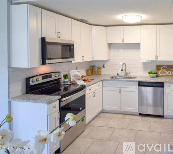 A kitchen with white cabinets and appliances, a sink, and a stove.