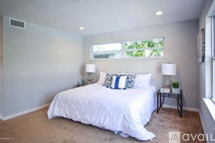 A bedroom with a large bed and two lamps.