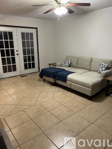 A living room with a couch and a fan.