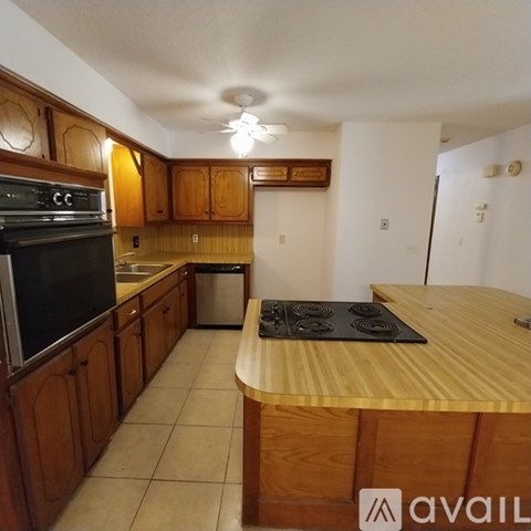 A kitchen with wooden cabinets and a black stove top.