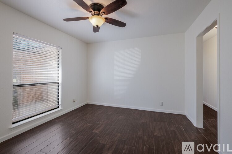 A room with a ceiling fan and wooden flooring.