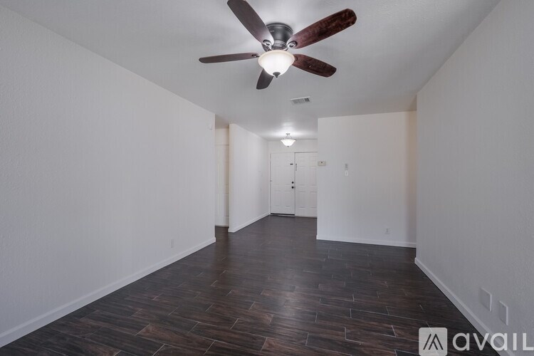 A room with a ceiling fan and wooden flooring.
