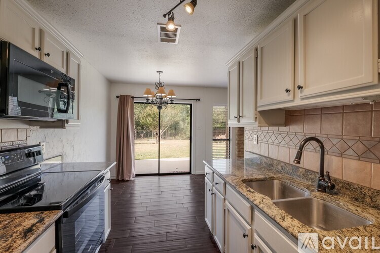 A kitchen with a black stove top oven and a granite counter top.