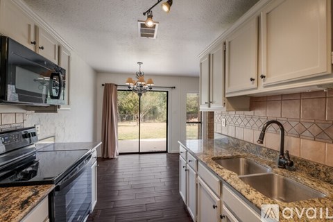 A kitchen with a black stove top oven and a granite counter top.