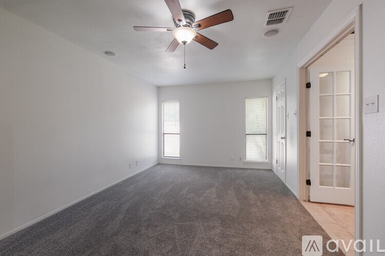 A room with a ceiling fan and carpeted floor.