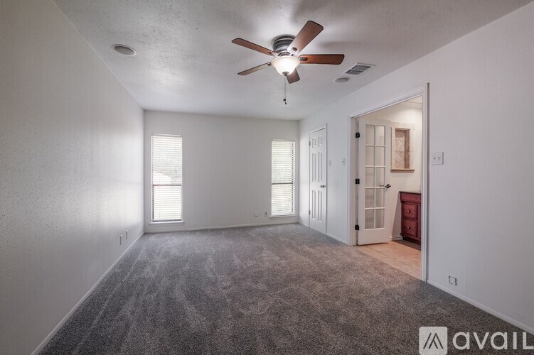 A room with a ceiling fan and carpeted floor.