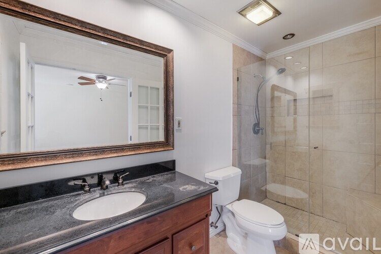 A bathroom with a toilet, sink, mirror and shower.