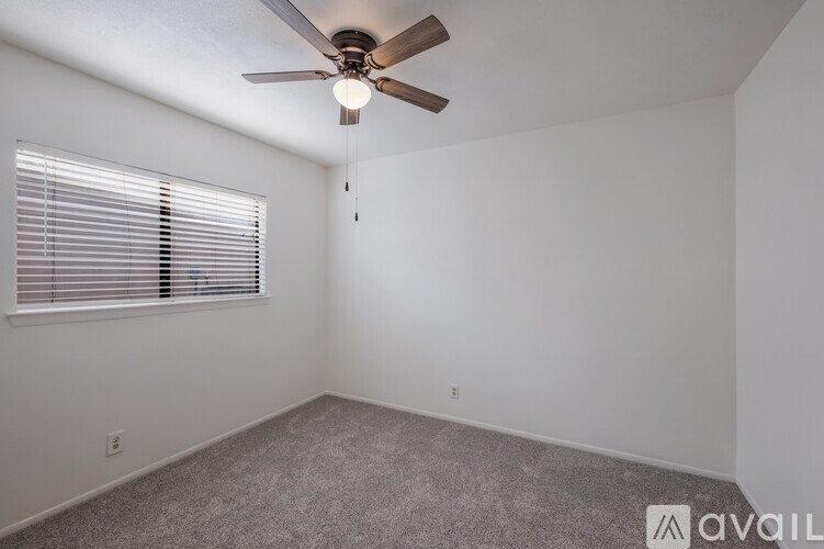 A room with a ceiling fan and a window with blinds.