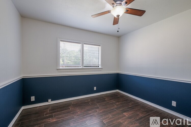 A room with a ceiling fan and a window with blinds.