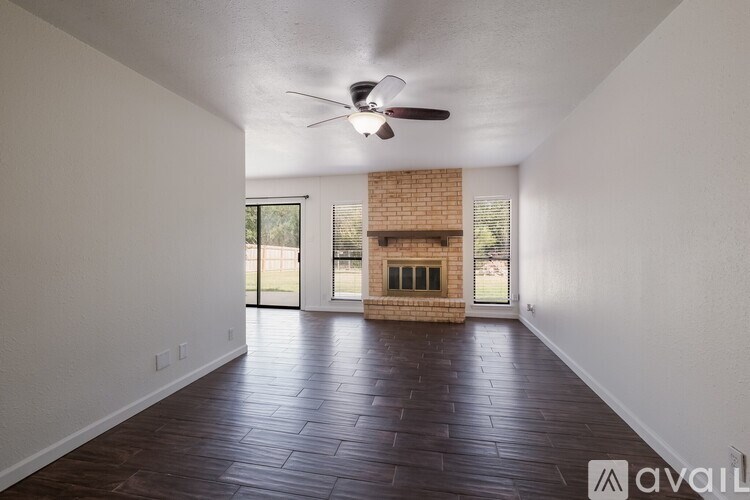A room with a ceiling fan and a brick fireplace.