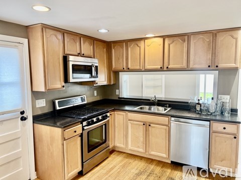 A kitchen with wooden cabinets and black countertops.