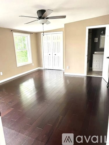 A room with a fan and wooden floors.