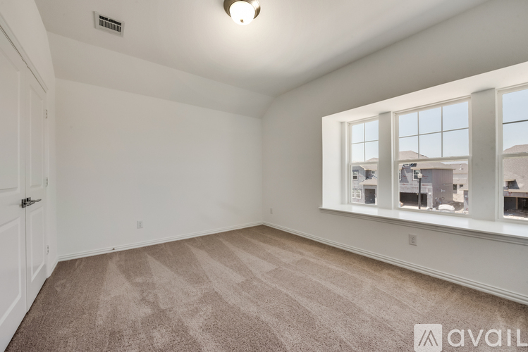 A room with a carpeted floor and a window showing a view of other buildings.