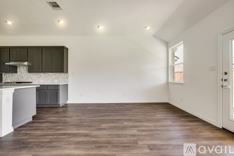 A spacious room with wooden flooring and a kitchen area with a stove top oven.