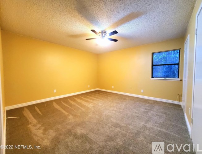 A room with a ceiling fan and a window.
