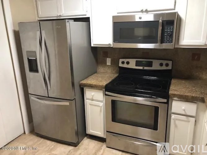 A kitchen with a stainless steel refrigerator, microwave, oven, and countertop.