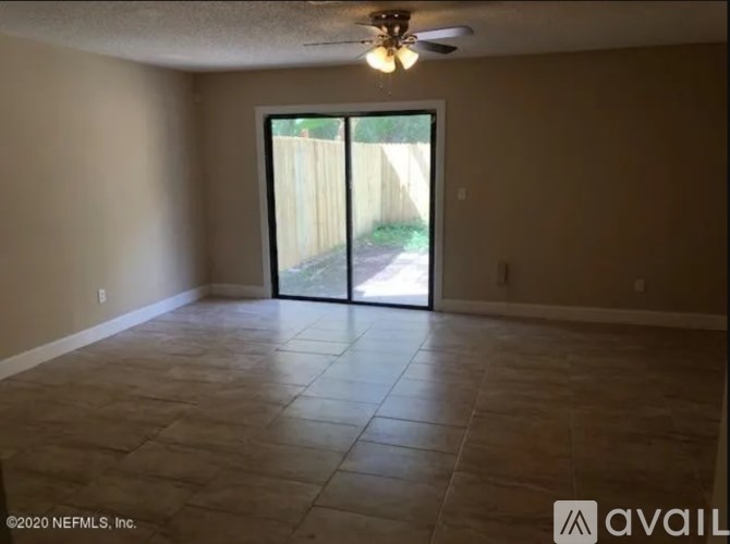 A room with a ceiling fan and sliding glass doors.