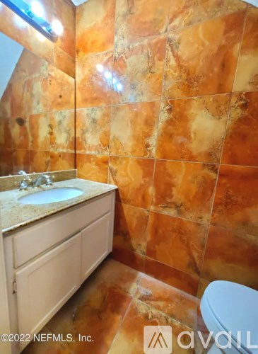 A bathroom with a brown tiled wall and a white toilet.