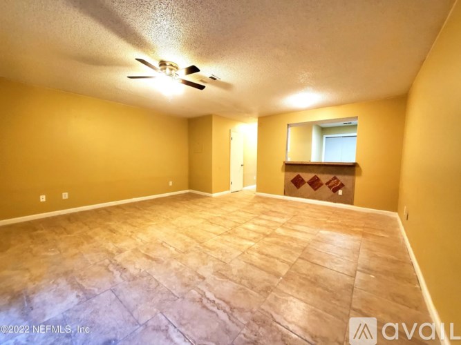 A room with a ceiling fan and a window with a view of a building outside.