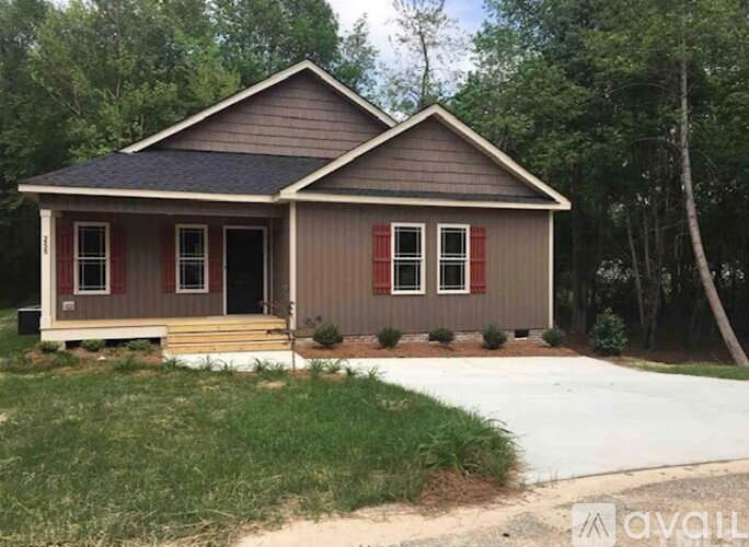 A small house with a brown roof and red window trim is for sale.