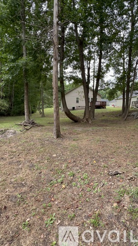 A grassy area with trees and a house in the background.
