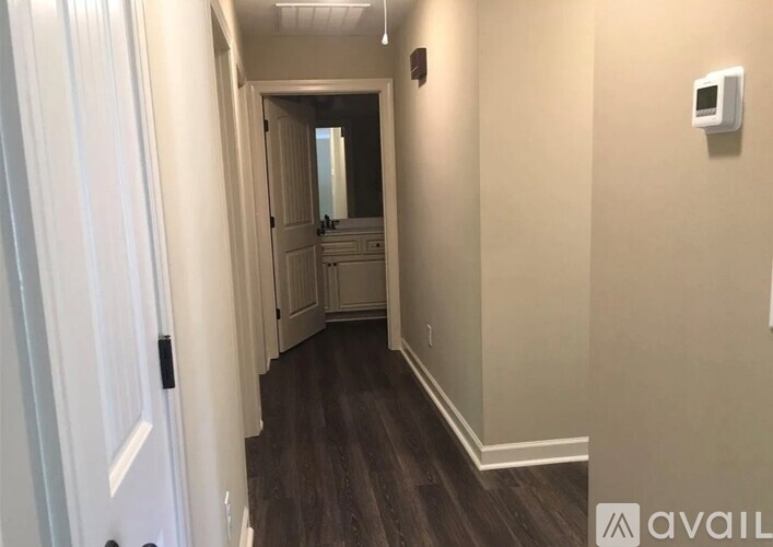 A hallway with a door on the left and a mirror on the wall.