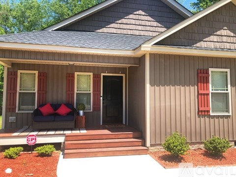 A house with a grey siding and a brown roof with a small porch.