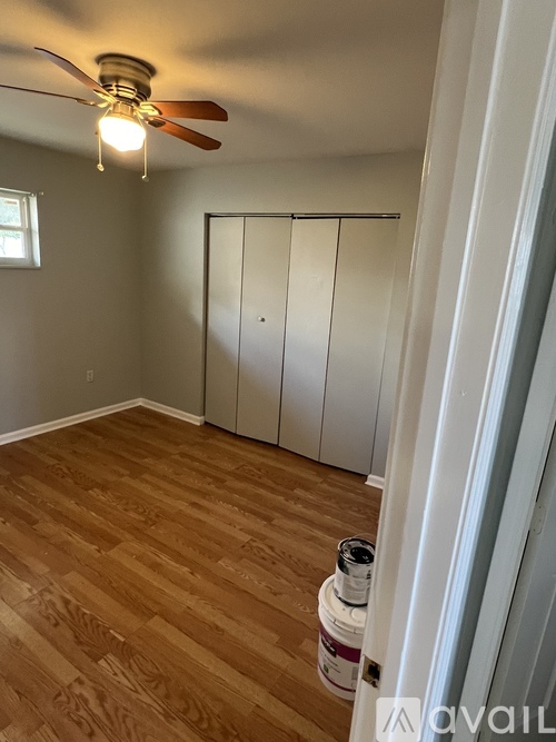 A room with a ceiling fan and wooden flooring.
