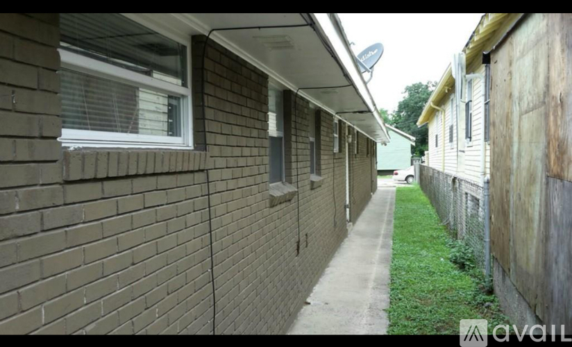 A long, narrow alley with a brick wall on one side and a wooden fence on the other.