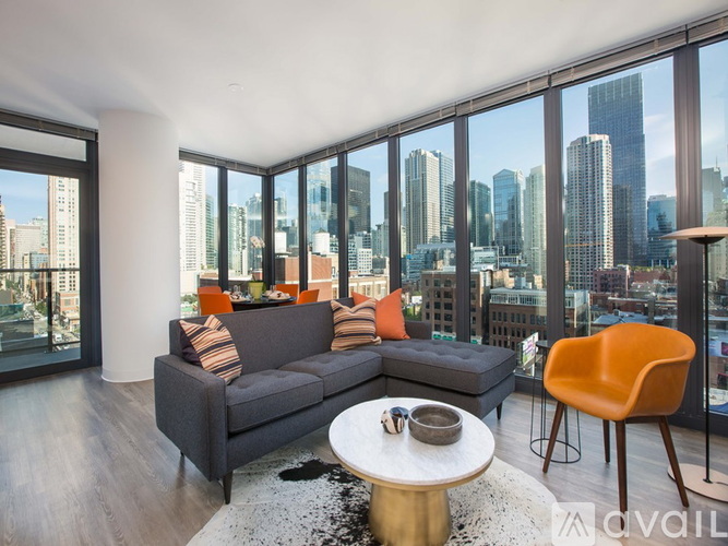 A modern living room with a grey sofa and a coffee table in front of a large window overlooking a cityscape.